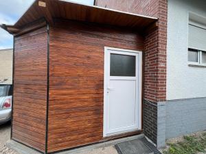 ein Holzgebäude mit einer weißen Tür an der Seite eines Gebäudes in der Unterkunft 1 Room in Hannover