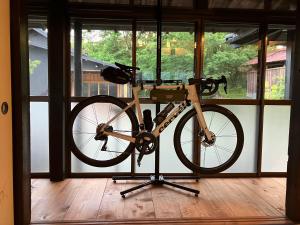 Una bicicleta en un stand en una habitación con ventanas en お宿でん吉, en Minami Aso