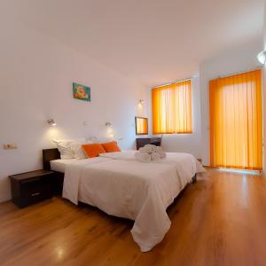 1 dormitorio con 1 cama grande con sábanas blancas y almohadas de color naranja en Sunny Holiday Apartments, en Sunny Beach