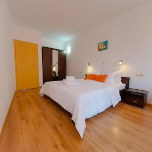 a bedroom with a large white bed and wooden floors at Sunny Holiday Apartments in Sunny Beach