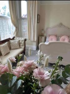 uma sala de estar com flores cor-de-rosa e um sofá em Baytree House em Lowestoft