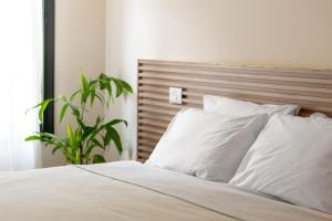 Un dormitorio con una cama con almohadas blancas y una planta en Slowness - Kibbutz Moran en Moran