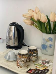 a tea pot and cups on a table with flowers at Quarto Nº5 FANTASTIQUE- Central Praia in Praia