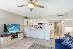 a living room with a blue couch and a ceiling fan at Emerald Isle 604 in St. Pete Beach