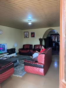 a person sitting on a couch in a living room at Yogi Home Stay Near Freetown Airport in Freetown