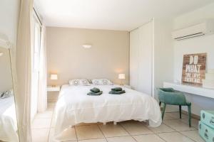 a white bedroom with a bed and a green chair at Just in Cap Canaille in Cassis