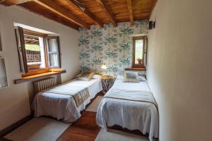2 Betten in einem Zimmer mit 2 Fenstern in der Unterkunft Finca La Casería LA CASA in Cangas de Onís