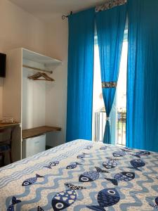 1 dormitorio con 1 cama con cortinas azules y ventana en Sunrise B&B Le castella, en Le Castella