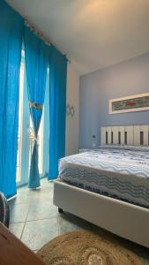 a bedroom with a bed with blue curtains and a window at Sunrise B&B Le castella in Le Castella