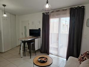 ein Wohnzimmer mit einem Tisch und einem Fenster in der Unterkunft Studio cosy proche toutes commodités avec parking gratuit in Mezzavia