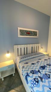 Schlafzimmer mit einem Bett mit einer blauen und weißen Bettdecke in der Unterkunft Sunrise B&B Le castella in Le Castella