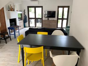 sala de estar con mesa negra y sillas amarillas en Villa del Brigante, 200m from the beach, 80m², 2 bedrooms, 4-5 persons, en Capitana