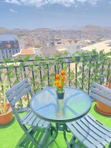 a glass table with flowers in a vase on a balcony at Quarto Nº5 FANTASTIQUE- Central Praia in Praia