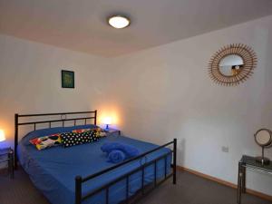 een slaapkamer met een bed met blauwe lakens en een spiegel bij L'amarre aux anges in Cormatin