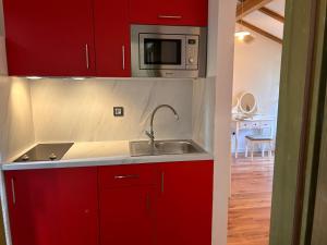 a red kitchen with a sink and a microwave at Gaya apartments in Šibenik