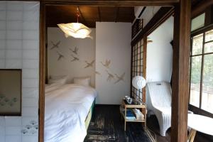 - une chambre avec un lit avec des oiseaux sur le mur dans l'établissement Villa Sacra ヴィラサクラ, à Kamakura