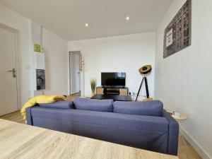 a living room with a blue couch and a tv at L'escapade - 2 chambres - 1 espace bureau in Gouesnou