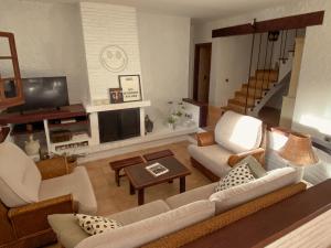 een woonkamer met een bank, stoelen en een tv bij Casa Magnolia in Dosríus