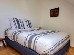 uma cama com almofadas listradas e uma fotografia na parede em Appartement dans le bourg du Guildo - Saint-Cast em Saint-Cast-le-Guildo