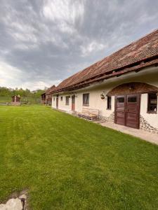 a building with a grass yard in front of it at Casa pe Valea Hartibaciului(Bărcuț) in Bărcuţ