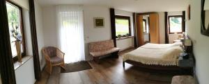 a bedroom with a bed and a chair and windows at Pension Garni Talblick in Baiersbronn