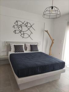 een witte slaapkamer met een bed met een zwart dekbed bij EmMi Houses in Ária