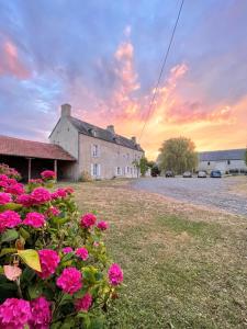 una casa con flores rosas delante de un patio en Ferme fortifiée d Enguenard, en Formigny