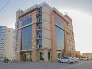 a building with cars parked in front of it at Tribes hotel in Sohar