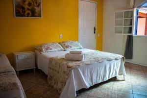 1 dormitorio con cama y pared amarilla en Pousadinha da Bia en Rio das Ostras