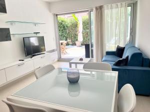 a living room with a glass table and a blue couch at Rêve de sable appartement avec jardin et parking in Menton