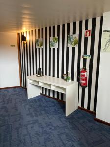 um quarto com uma mesa branca e uma parede listrada a preto e branco em Vinha da Areia Beach Hotel em Vila Franca do Campo