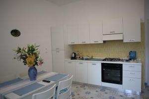 una cocina con armarios blancos y un jarrón de flores sobre una mesa en mary's apartment, en Maiori