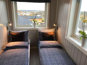 two beds in a small room with two windows at Topp moderne suite. in Larvik