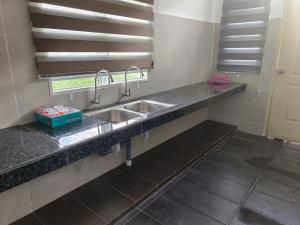 a kitchen counter with two sinks and a window at HOMESTAY MYROKMA in Kampong Belukar