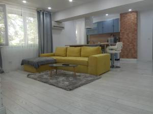 uma sala de estar com um sofá amarelo e uma mesa em Apart Maya em Calafat