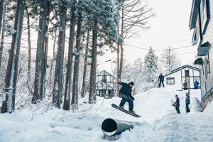 Mountain Hut Myoko في ميوكو: رجل يركب لوح ثلج على منحدر مغطى بالثلج