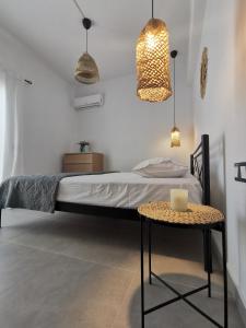 a bedroom with a bed with a table and pendant lights at Mantalena's house in Antiparos