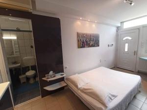 a bedroom with a white bed and a bathroom at Takis house in Rafina