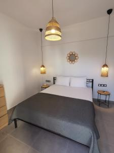 a bedroom with a large bed and two pendant lights at Mantalena's house in Antiparos
