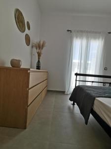 a bedroom with a bed and a dresser and a window at Mantalena's house in Antiparos