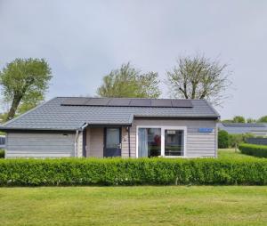 a house with solar panels on the roof at Het Dobbertje, charmant houten huisje in Sint Maartensvlotbrug