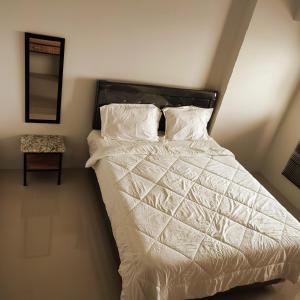 a bed with white sheets and pillows in a bedroom at DeAr UC Apartment in Surabaya