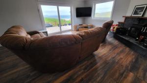 a brown leather couch sitting in a living room at Beachview Villa on Scottish Highland Coast NC500 With Hot Tub in Rhiconich