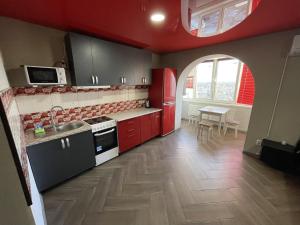 a kitchen with red cabinets and a sink and a table at Studio apartment on Vatutina in Vinnytsya