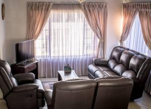 Entire Self catering Home in Springs في سبيرنغز: غرفة معيشة مع أريكة جلدية وتلفزيون
