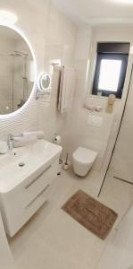 een witte badkamer met een wastafel en een spiegel bij Apartment Agnes with 63 m2 Rooftop Terrace, Grill and Pool in Okrug Gornji
