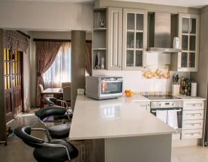 a kitchen with a counter with a microwave and chairs at Entire Self catering Home in Springs in Springs