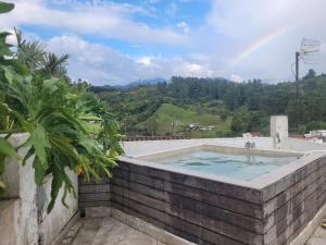 a hot tub with a rainbow in the background at Hostal Hilltop Salento in Salento