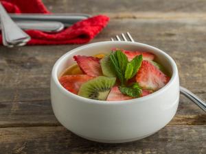 a bowl of soup with strawberries and mint on a table at Al Liwan Suites Rawdat Al Khail in Doha