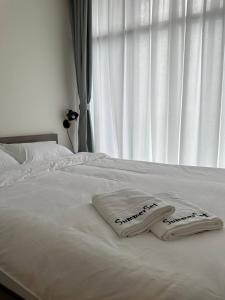 a white bed with two towels on it with a window at Summer Studio Apartment at Kota Kinabalu City Centre in Kota Kinabalu